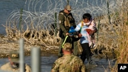 FILE - Migrants are taken into custody by officials at the Texas-Mexico border, in Eagle Pass, Texas, Jan. 3, 2024.