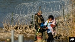 FILE - Migrants are taken into custody by officials at the Texas-Mexico border, in Eagle Pass, Texas, Jan. 3, 2024.