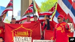 Lahaina residents and their supporters hold signs and flags at the Hawaii State Capitol in Honolulu, Oct. 3, 2023, at a news conference about a petition asking Hawaii Gov. Josh Green to delay reopening a portion of West Maui to tourism. 