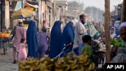 করাচির এক আফগান-অধ্যুষিত এলাকায় নীল বোরকা পরা আফগান নারী বাজার করছেন। ফটোঃ ২৬ জানুয়ারি, ২০২৪। 