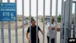 FILE - This picture taken on July 19, 2023, shows men at the gates of a Uyghur cemetery in Yengisar in northwest China's Xinjiang region.