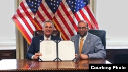 美國國會眾議院議長凱文·麥卡錫(左)拿著他已簽字的《美台21世紀貿易倡議首批協定實施法》與眾議院籌款委員會主席傑森·史密斯眾議員合影。 (眾議員傑森··史密斯辦公室提供）