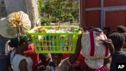 Neighbors pass in and out of a passageway as others erect a metal gate as protection against gangs in the Petion-Ville neighborhood of Port-au-Prince, Haiti, April 20, 2024.