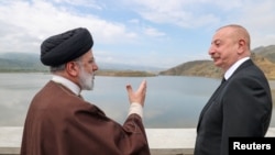 প্রেসিডেন্ট ইব্রাহিম রাইসি (বাঁয়ে) আজেরবাইজানের প্রেসিডেন্ট ইলহাম আলিয়েভের সাথে একটি বাঁধ উদ্বোধন করে ইরানে ফেরার পথে দুর্ঘটনার কবলে পড়েন। ফটোঃ ১৯ মে, ২০২৪।