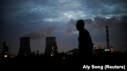 Seorang pria berjalan melewati pembangkit listrik tenaga batu bara di Shanghai, China, 14 Oktober 2021. (Foto: REUTERS/Aly Song)