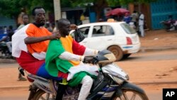 Nigeriens with Russian and Nigerien flags head for an anti-French protest in Niamey, Niger, Aug. 11, 2023.