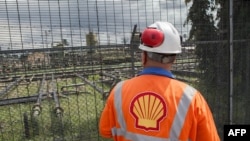 FILE - An employee at the Shell Agbada 2 flow station looks at the station from behind a gate in Port Harcourt, Sept. 30, 2015. Oil companies like Shell have often blamed theft and sabotage for oil spills, a claim contested by environmental groups. 