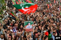 Pakistan Tehreek-e-Insaf (PTI) party supporters hold portraits of former prime minister Imran Khan, as they protest against the alleged skewing in country's national election, in Peshawar, March 10, 2024.