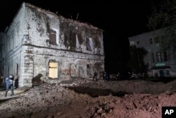 Police walk in front of a crater after a Russian rocket attack on a mental hospital in Kharkiv, Ukraine, April 27, 2024.