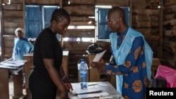 An independent National Electoral Commission agent processes a voter at the Nyabushongo Institute polling center on the second day of the Presidential election in Goma, North Kivu province of the Democratic Republic of Congo, Dec. 21, 2023.