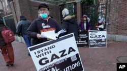 FILE - George Stevens hands out leaflets to passers-by near an entrance to Harvard University, Dec. 12, 2023, in Cambridge, Massachusetts, while joining pro-Palestinian demonstrators during a protest held to call for an end to the war in Gaza.