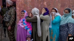 Kashmiri women hide their faces from cameras as they wait outside a polling station to cast their votes during the fourth phase of India's national elections, on the outskirts of Srinagar, Indian-administered Kashmir, May 13, 2024.