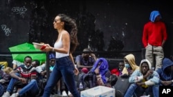 Des piétons croisent des migrants qui attendent dans une file d'attente à l'extérieur de l'hôtel Roosevelt qui est utilisé par la ville comme logement temporaire, le 31 juillet 2023, à New York.