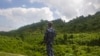 FILE - A Myanmar police officer stands on a road as they provide security at a checkpoint in Buthidaung, Rakhine State, western Myanmar on May 28, 2017. 