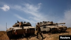 Seorang tentara Israel berjalan di samping tank yang berada di dekat perbatasan Israel-Jalur Gaza, pada 2 Mei 2024. (Foto: Reuters/Amir Cohen)