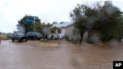 A resident checks flood waters surrounding his home during a downpour in Palmdale, California, as a tropical storm moves into the area, Aug. 20, 2023.