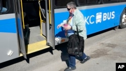 FILE - A woman boards a bus in Kansas City, Mo., March 3, 2021.
