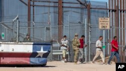 FILE - Under the watch of a U.S. Army soldier, migrants enter into El Paso, Texas, from Ciudad Juarez, Mexico, May 10, 2023.