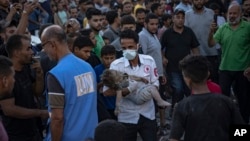A child is carried from the rubble of a building after an airstrike in Khan Younis, Gaza Strip, Oct. 21, 2023.