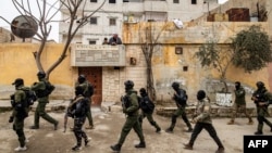 FILE - Syrian Kurdish Asayish security forces search houses during a raid against suspected Islamic State group fighters in Raqqa, Syria, Jan. 28, 2023.