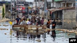 People cross floodwaters in the Pompage district of Kinshasa, Democratic Republic of Congo, on Jan. 9, 2024, following heavy rains. Regional flooding left some 350,000 people in need of humanitarian aid in neighboring Republic of Congo.
