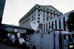 Media vehicles stage outside the Fulton County Courthouse in Atlanta, Aug. 14, 2023.