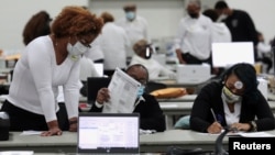 FILE - Poll workers tabulate absentee ballots at the TCF Center during Election Day in Detroit, Nov. 3, 2020.