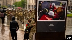An army comrade is comforted as he cries during the funeral ceremony of Ukrainian army paramedic Nazarii Lavrovskyi, 31, killed in the war, at Independence square in Kyiv, April 24, 2024.