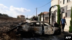 People look at a burnt car a day after an attack by Jewish settlers on the village of Jit near Nablus in the West Bank on Aug. 16, 2024.