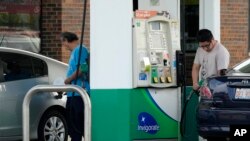 People check their gas tanks after filling up their vehicles at a gas station in Wheeling, Illinois, May 16, 2024. 