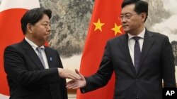 Japanese Foreign Minister Yoshimasa Hayashi, left, shakes hands with his counterpart Qin Gang at the Diaoyutai State Guest House in Beijing, April 2, 2023. (Kyodo News via AP)