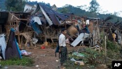 FILE - A man looks at homes destroyed after air and artillery strikes in Mung Lai Hkyet displacement camp, in Laiza, Myanmar, Oct. 10, 2023.