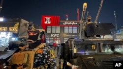 FILE - Iraqi security forces stand guard in front of Kentucky Fried Chicken restaurant in Baghdad, June 5, 2024. 