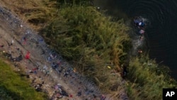 Migrants use a raft to cross the Rio Grande at the Texas-Mexico border, May 11, 2023, in Brownsville, Texas.