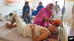 一名妇女在印度北方邦的一所医院里用湿布擦拭她生病的兄弟的头部，让他在热浪中保持凉爽。(2023年6月19日)