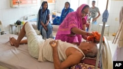 A woman wipes the head of her brother to keep him cool from the heat wave at the district hospital in Ballia, Uttar Pradesh state, India, June 19, 2023. A scorching heat wave has overwhelmed hospitals and morgues in two of India's most populous states. 