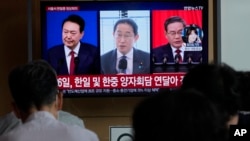 A TV screen shows file images of South Korean President Yoon Suk Yeol, left, Japanese Prime Minister Fumio Kishida and Chinese Premier Li Qiang, right, during a news program at the Seoul Railway Station in Seoul, South Korea, Thursday, May 23, 2024. 