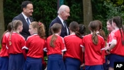 U.S. President Joe Biden and Ireland's Taoiseach Leo Varadkar talk with children after watching a youth Gaelic sports demonstration at Farmleigh House, April 13, 2023, in Dublin.