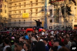 People gather to watch a concert after the welcoming ceremony of the Belem, the three-masted sailing ship which is carrying the Olympic flame, at the Old Port in Marseille, southern France, May 8, 2024.