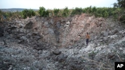 A Lebanese villager checks a huge crater that was made by an Israeli airstrike, in Qalili village, south Lebanon, April 7, 2023.
