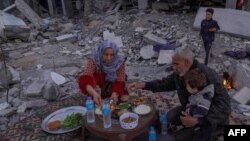 একটি ফিলিস্তিনি পরিবার গাজার দেইর আল বালাহ-তে তাদের বিধ্বস্ত বাড়ির সামনে ইফতারের প্রস্তুতি নিচ্ছে। ১১ মার্চ, ২০২৪। 