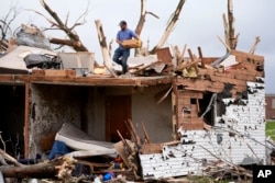 A man sorts through the remains of a home damaged by a tornado, in Greenfield, Iowa, May 21, 2024.