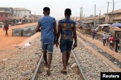 FILE - Chris Agiriga, 23, one of the Nigerian men arrested on charges of public display of affection with members of the same sex, walks with a friend on the streets of Mushin in Lagos, Feb. 14, 2020.