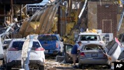 Hugo Parra, of Farmers Branch, Texas, collects belongings from his vehicle after he rode out a tornado with about 40 others in the bathrooms of a truck stop the previous night, May 26, 2024, in Valley View, Texas. 