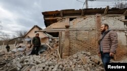 Men stand near buildings damaged in recent shelling in the course of Russia-Ukraine conflict in Donetsk, Russian-controlled, Ukraine, March 12, 2023. 
