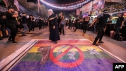 FILE - Shiite Muslims self-flagellate over an unfurled banner depicting the pride rainbow flag defaced with a boot and the Arabic words "no to a homosexual society," in Nasiriyah in Iraq's southern Dhi Qar province, July 25, 2023.