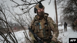 A serviceman, call sign 'Virus,' of the Ukrainian Armed Forces Vedmak ('Witcher') unit patrols on the front line near Bakhmut on Feb. 18, 2023.