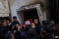 Mourners carry the body of Montaser Shawwa, 16, out of the family house, during his funeral in the West Bank refugee camp of Balata, Nablus, Tuesday, Feb. 21, 2023.