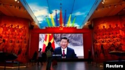 Pengunjung berdiri di depan layar raksasa yang menampilkan Presiden China Xi Jinping di samping bendera Partai Komunis China, di Museum Militer Revolusi Rakyat China di Beijing, China 8 Oktober 2022. (Foto: REUTERS/Florence Lo)