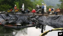 ARCHIVO - En esta fotografía publicada por Oleoducto de Crudos Pesados, trabajadores limpian crudo después de un derrame cerca de la aldea de Santa Rosa en Ecuador, el jueves 26 de febrero de 2009.